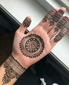 a person's hand with henna tattoos on their palm and fingers, showing the intricate design