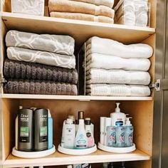 an organized bathroom cabinet with lots of towels and toiletries on it's shelves