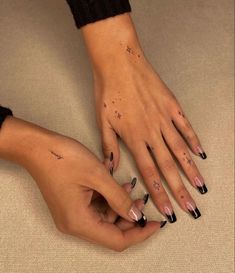 two hands with black and white nail polishes on their fingers, one holding the other's hand