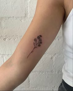 a woman's arm with a small flower tattoo on the left side of her arm