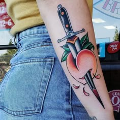 a woman with a tattoo on her arm holding a knife and an apple in the background