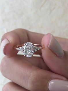 a woman's hand holding an engagement ring in her left hand, with the center diamond