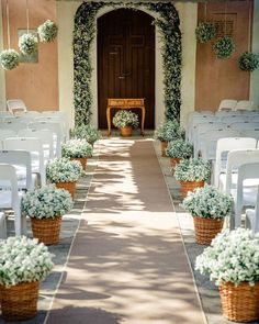 an outdoor wedding ceremony with white chairs and flowers in the baskets on each side of the aisle