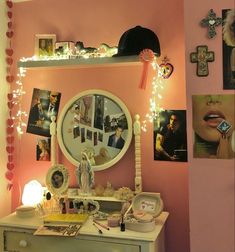 a bedroom with pink walls and pictures on the wall, including a vanity mirror that has been decorated with lights