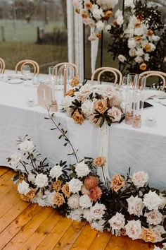 an arrangement of flowers and candles on a table at a wedding reception in front of a large window