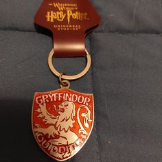 a red and gold keychain with a hogwarts badge on it's side