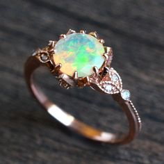 an opal and diamond ring sitting on top of a wooden table