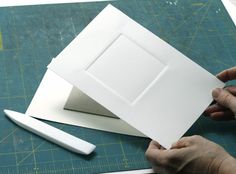 a person is cutting out some white paper