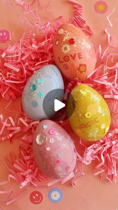 three decorated easter eggs sitting on top of pink shredded paper