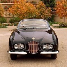 an old black car parked in front of a house