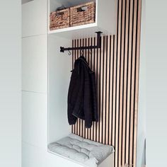 a coat rack with two coats hanging on it and a bench in front of it