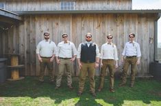 a group of men standing next to each other in front of a wooden building with sunglasses on