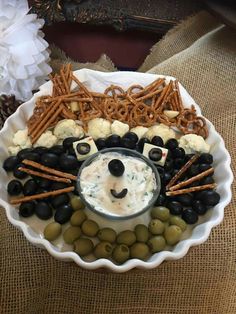 a plate with black olives, pretzels and cheese in the shape of a face