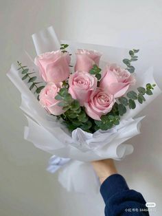 a person holding a bouquet of pink roses