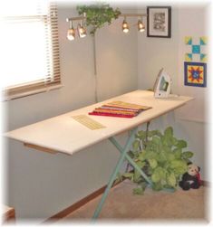 a room with a white table and some pictures on the wall next to a potted plant