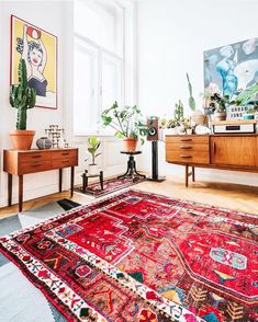 a living room filled with lots of furniture and plants on top of a red rug