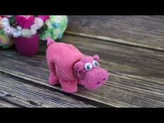 a pink stuffed animal sitting on top of a wooden table next to flowers and potted plants