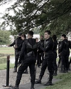 a group of men standing next to each other in front of a tree and water