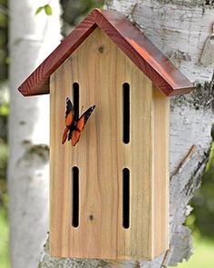 a wooden birdhouse with two butterflies on it's side hanging from a tree