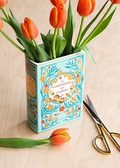 there is a small tin with flowers in it next to some scissors and a pair of scissors