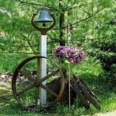 an old water wheel with a flower pot in the center and a wind chime attached to it