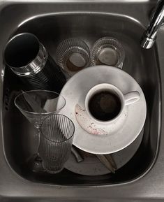 dirty dishes and cups in a stainless steel sink