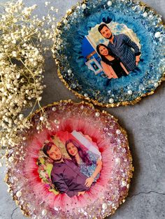 two decorative plates with pictures on them sitting next to flowers and baby's breath