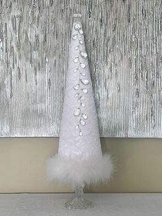 a small white christmas tree sitting on top of a table next to a silver wall