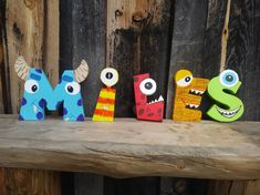 three wooden letters with different colored monsters on them