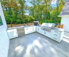 an outdoor kitchen with white cabinets and stainless steel appliances