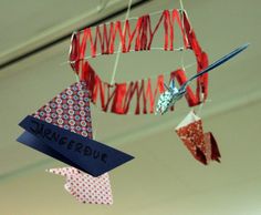 some red white and blue paper decorations hanging from the ceiling with scissors in each one