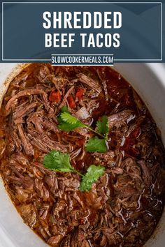 shredded beef tacos in a white bowl with cilantro garnishes