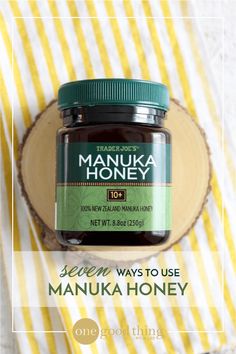 a jar of manuka honey sitting on top of a piece of wood next to a yellow and white towel