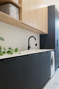 a washer and dryer in a small room with wooden cabinetry, white tile flooring and black cabinets