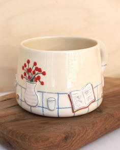 a white vase with red flowers in it sitting on a wooden board