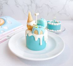 there is a blue cake with ice cream on it and two cakes in the background