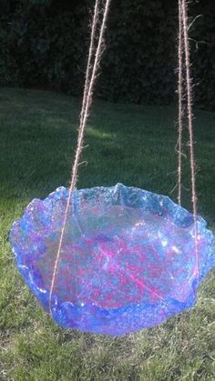 a blue bowl hanging from a rope in the grass