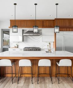 a kitchen with an island, stove and four stools in front of the counter