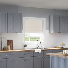 a kitchen with gray cabinets and wooden counter tops