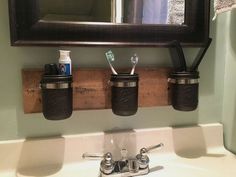 three toothbrushes and two toothpaste holders are hanging on the wall above a bathroom sink