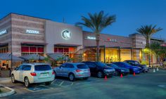 several cars are parked in front of a pizza hut at night with palm trees and umbrellas