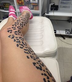 a woman's legs with black and white animal print tattoos on them, sitting in front of a vending machine