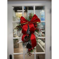 a red and white christmas wreath hanging on the side of a glass door in front of a window