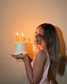 a woman holding a cake with lit candles on it