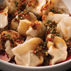 a white bowl filled with dumplings covered in sauce