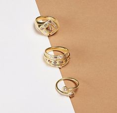 three gold rings sitting on top of a white and brown paper next to each other