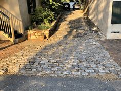 an empty cobblestone street with cars parked on the side