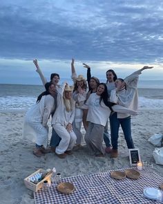 a group of women standing next to each other on top of a sand covered beach