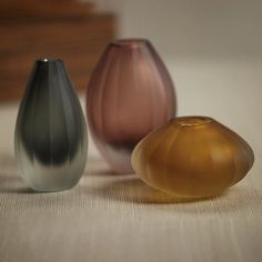 three different colored vases sitting on top of a table