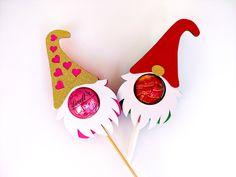 two candy lollipops in the shape of gnome's hats with hearts on them